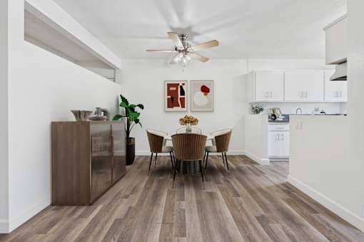 A dining room with a wooden floor and a white ceiling fan.