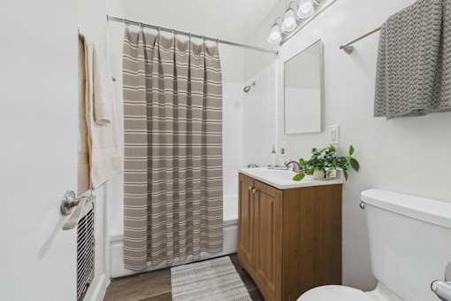 A bathroom with a white tub, a wooden cabinet, and a shower curtain.