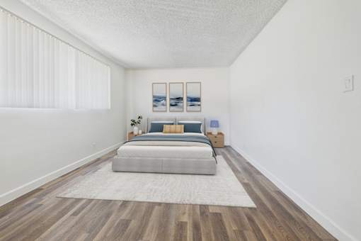 A bedroom with a bed, pillows, a nightstand, a rug, and pictures on the wall.