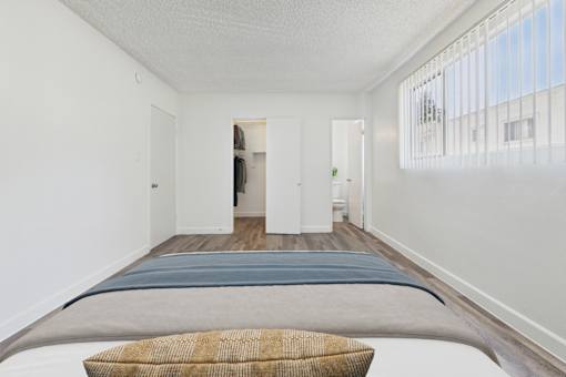 A bedroom with a bed and a window with blinds.
