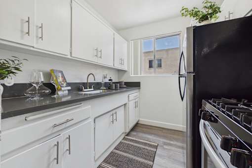 A kitchen with white cabinets and a black refrigerator.