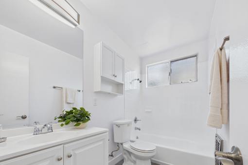 A white bathroom with a toilet, sink, and mirror.