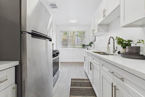 A modern kitchen with white cabinets and a stainless steel refrigerator.