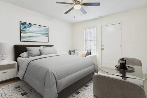 A bedroom with a bed, chair, and a ceiling fan.