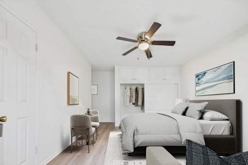 A bedroom with a bed, chair, and a ceiling fan.