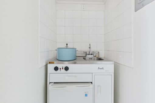 A white kitchen with a blue pot on the stove.