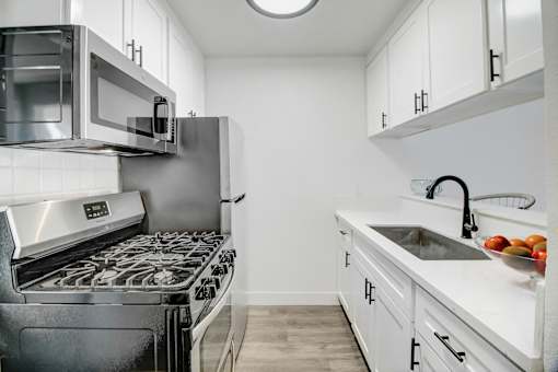 a kitchen with white cabinets and stainless steel appliances and a sink