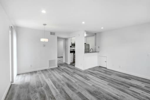 the living room and kitchen of a new home with white walls and wood flooring