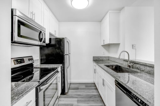 an all white kitchen with stainless steel appliances and marble counter tops