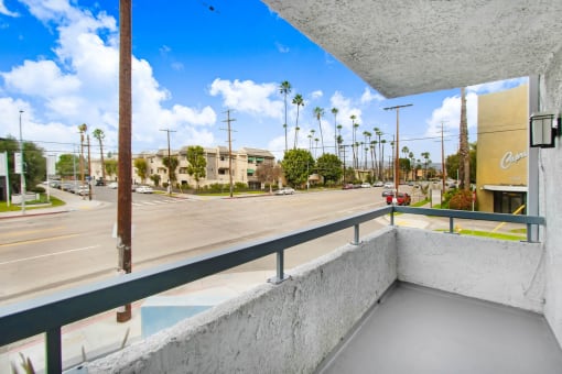 a balcony with a view of a street and palm trees