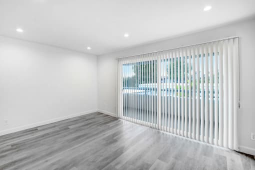 an empty living room with a large window with blinds