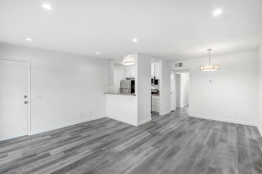 the living room and kitchen in a new home with white walls and wood flooring