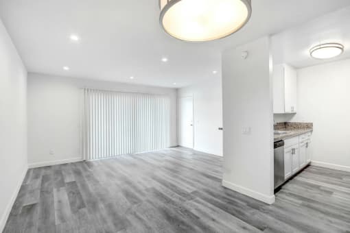 the living room and kitchen of a new home with white walls and wood flooring