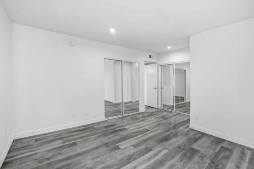 a renovated living room with white walls and a mirrored closet