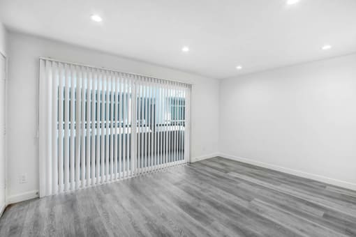 an empty living room with a white wall and a sliding glass door