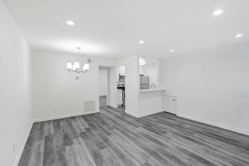the living room and kitchen in a new home with white walls and wood flooring