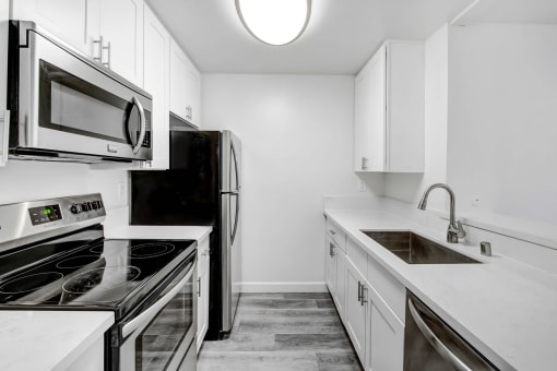 an all white kitchen with stainless steel appliances and white cabinets