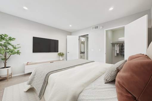 A bedroom with a large bed and a flat screen TV mounted on the wall.