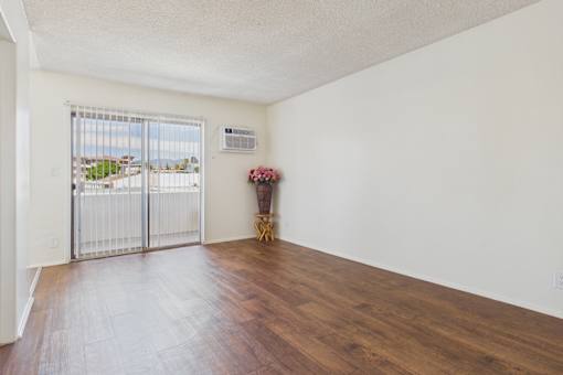 A room with a sliding glass door leading to a balcony.