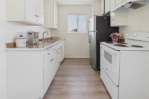 A kitchen with white appliances and wooden floors.
