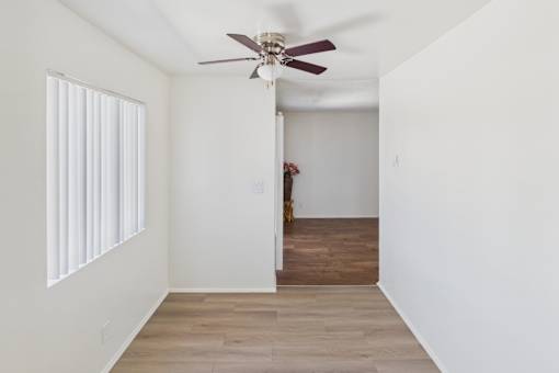 A room with a ceiling fan and a doorway leading to another room.