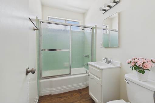 A white bathroom with a glass shower door and a white sink.
