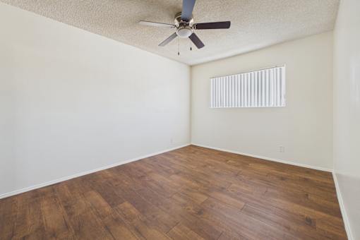 Empty room with wooden floor and ceiling fan.
