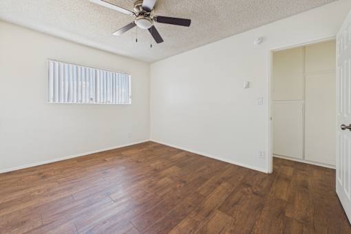 A room with a ceiling fan and wooden flooring.