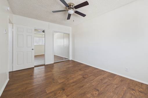 A room with a ceiling fan and wooden flooring.