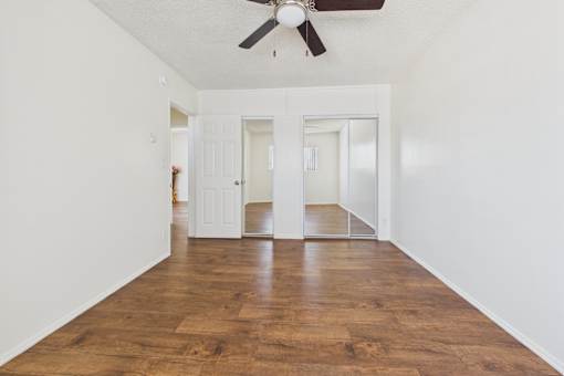 A room with a ceiling fan and wooden floors.