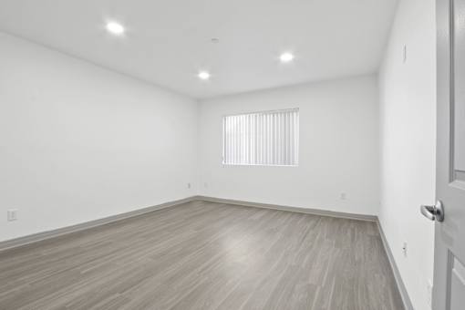 A room with a wooden floor and a window with blinds.