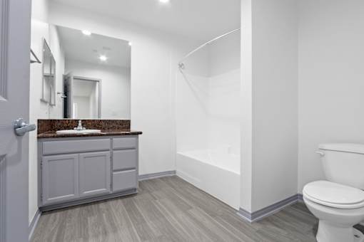 A bathroom with a toilet, sink, and mirror.