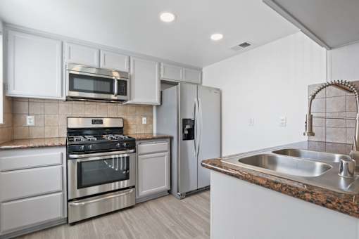 A kitchen with a stove, oven, refrigerator, and microwave.