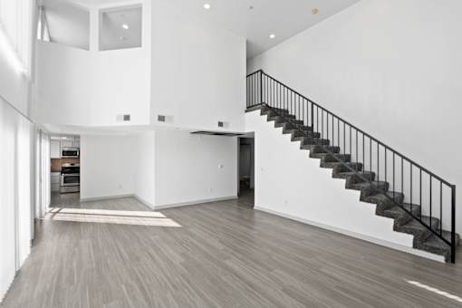 A spacious interior of a house with a staircase and a kitchen area.