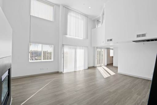 A spacious room with wooden floors and white walls.