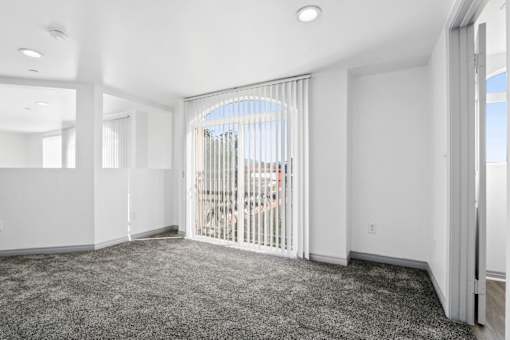 A room with a carpeted floor and a sliding glass door.