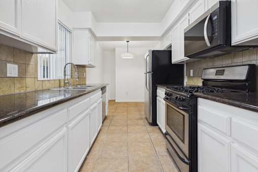 A kitchen with black appliances and white cabinets.