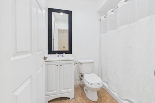 A white bathroom with a toilet and a mirror.
