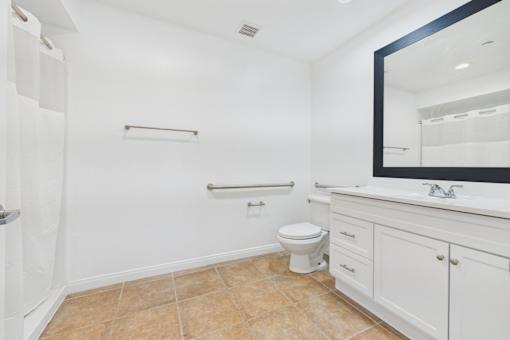 A white bathroom with a toilet, sink, and a mirror.