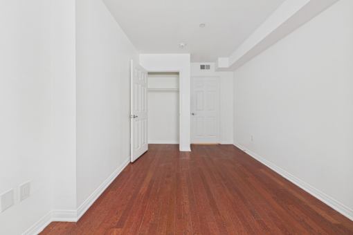 A long hallway with wood floors and white walls.