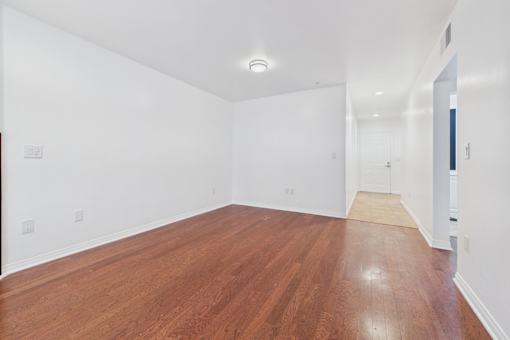 A long empty room with wooden floors and white walls.