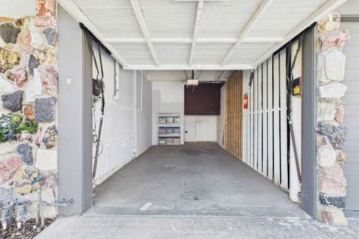 A long, narrow hallway with a white ceiling and stone walls.