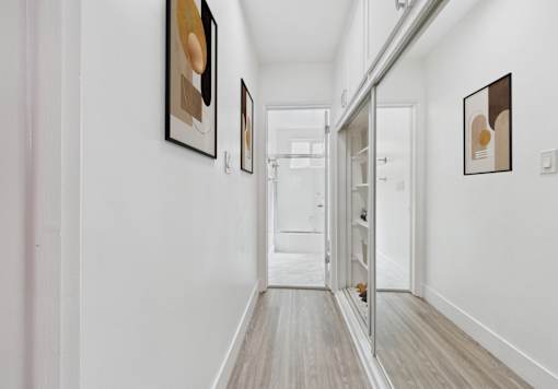 A hallway with white walls and a wooden floor.