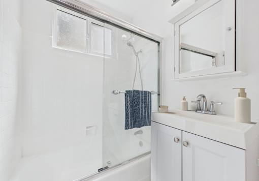 A white bathroom with a shower and a sink.