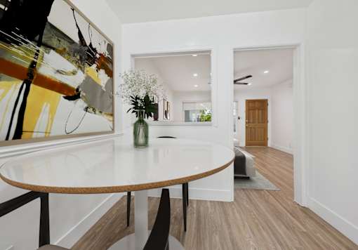 A modern dining room with a white table and a large abstract painting on the wall.