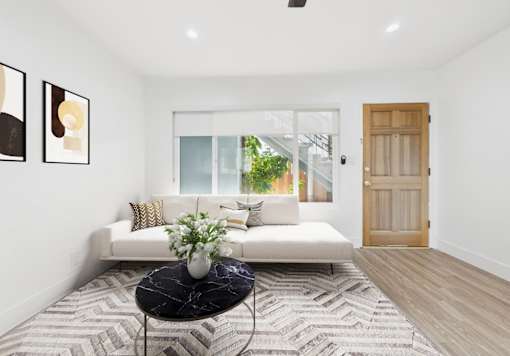 A living room with a white couch, a black coffee table, and a wooden door.