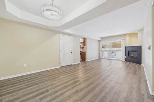 A spacious living room with wood flooring and a fireplace.