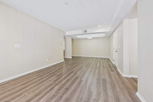 A long, empty hallway with wooden flooring and white walls.
