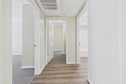 A long hallway with white walls and a carpeted floor.