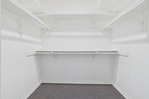 A white room with a grey carpet and a white shelf.